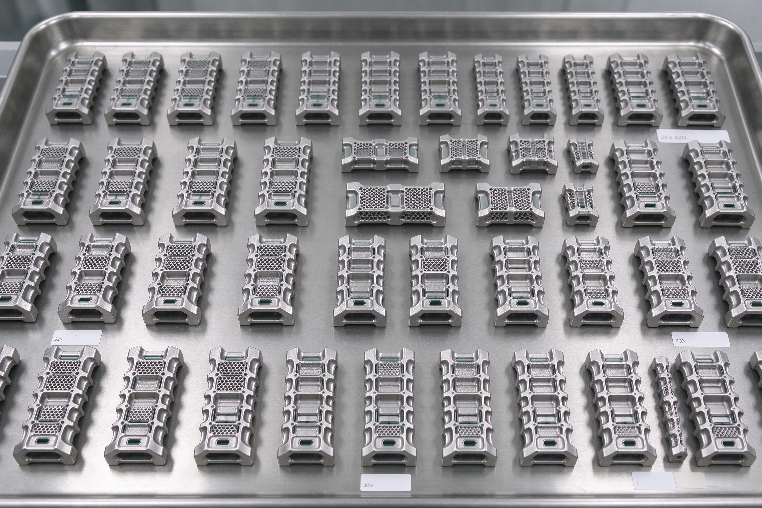 Batch of 50 finished titanium spinal interbody cages on a QC tray with batch labels